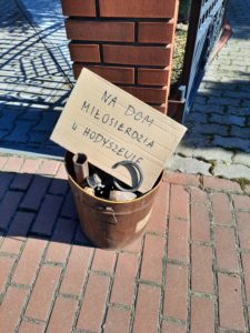 Wiaderko wypełnione złomem, na którym znajduje się napis zachęcający do wsparcia Domu Miłosierdzia i Hodyszewa. Zbiórka organizowana przez Fundację Pojednanie z Hodyszewa.