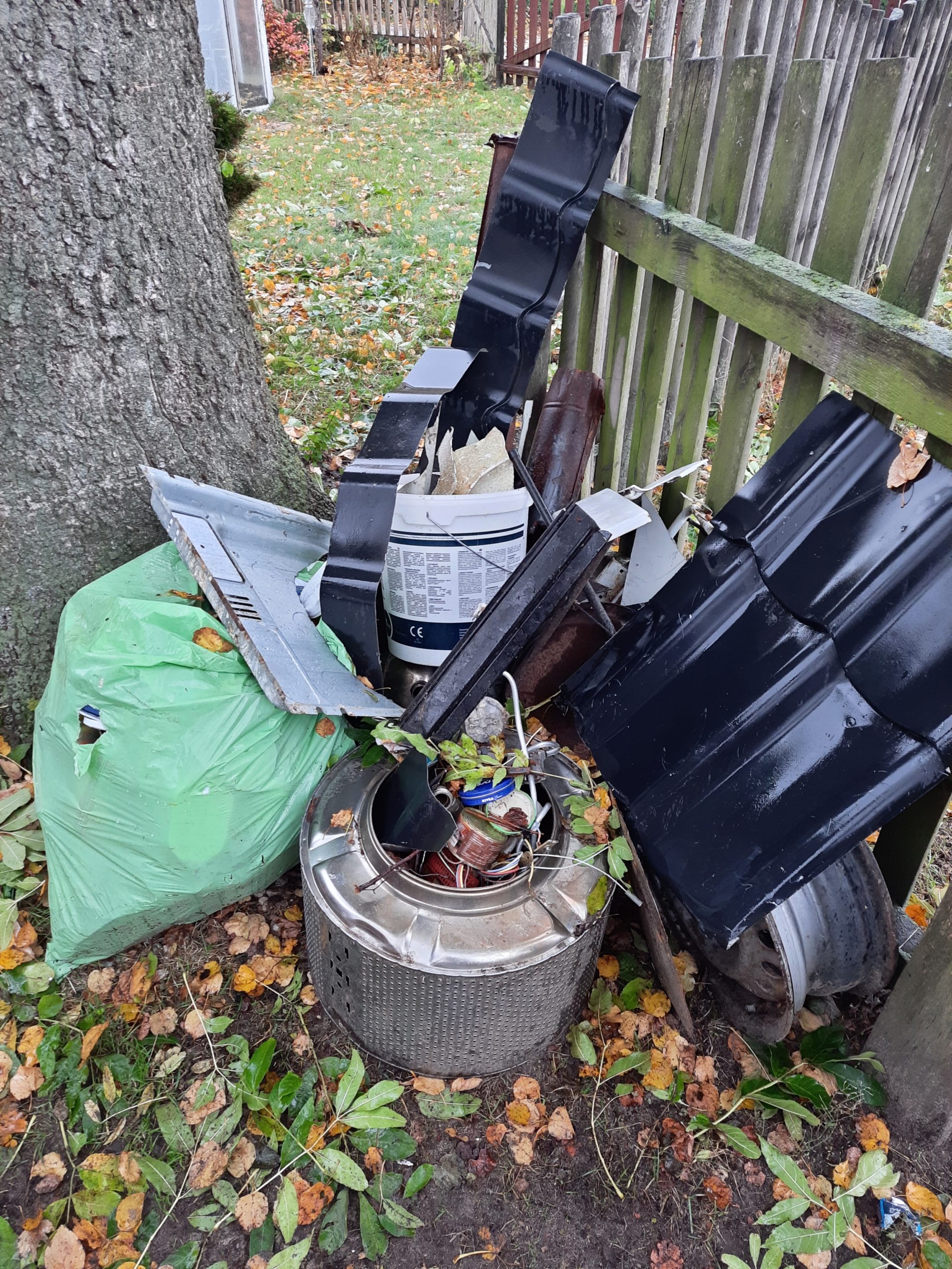 Zbiórka złomu, w tym fragmenty rynien i metalowych pojemników, znajduje się na trawniku obok domu. Użyte do identyfikacji materiałów do recyklingu. Osobę nie można zidentyfikować.