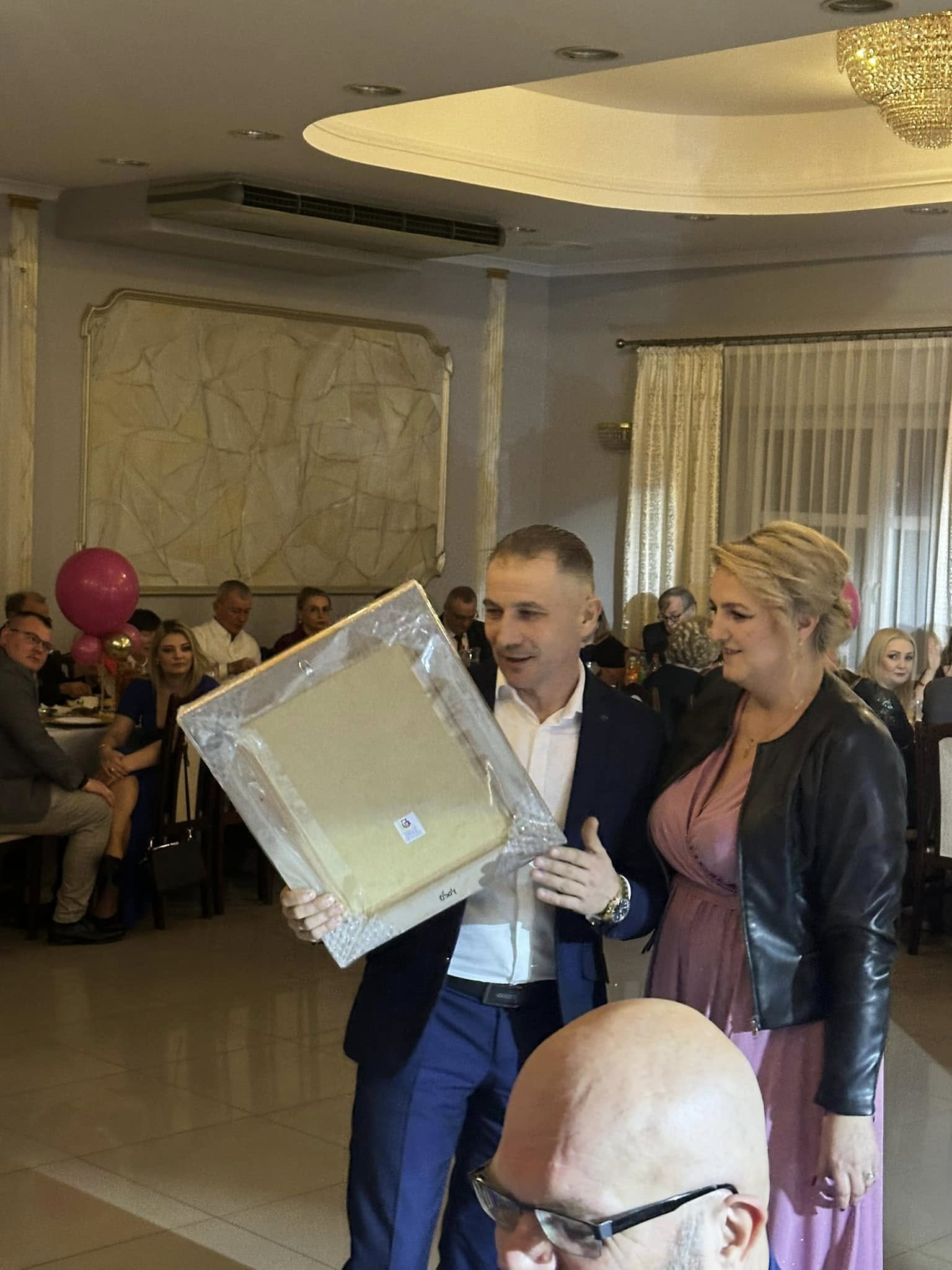 Para prezentuje oprawioną pracę uczestnikom Balu Charytatywnego Fundacji Pojednanie.