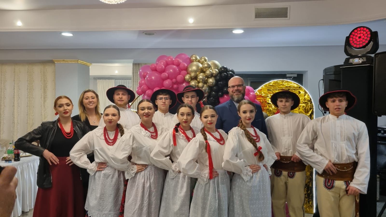 Zespół w strojach ludowych i dwoje gości pozują do zdjęcia podczas Balu Charytatywnego Fundacji Pojednanie.